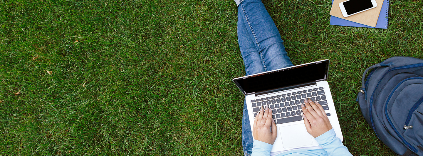 student on laptop sitting on grass